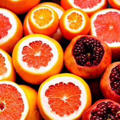 Halved grapefruits, oranges, and pomegranates displaying vibrant red citrus flesh