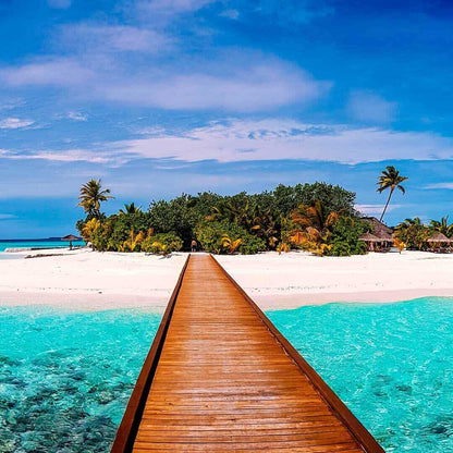 Wooden boardwalk leading to a tropical island with turquoise waters and white sand beach