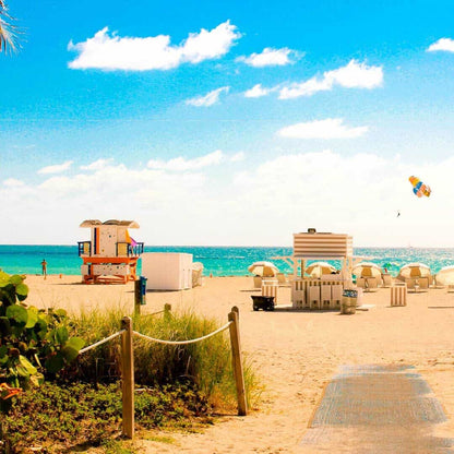 Sunny Miami Beach shoreline with lifeguard stand, striped umbrellas, and turquoise ocean