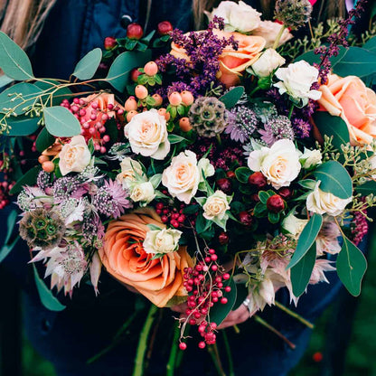 Lush bridal bouquet with peach roses and berries, ideal for wedding venue scenting