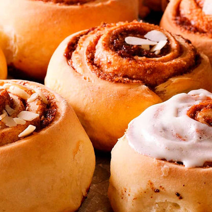 Freshly baked cinnamon rolls with icing and sliced almonds on parchment