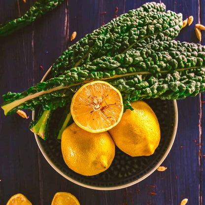 Fresh kale leaves and sliced lemons in a dark bowl, lemon lemongrass aroma
