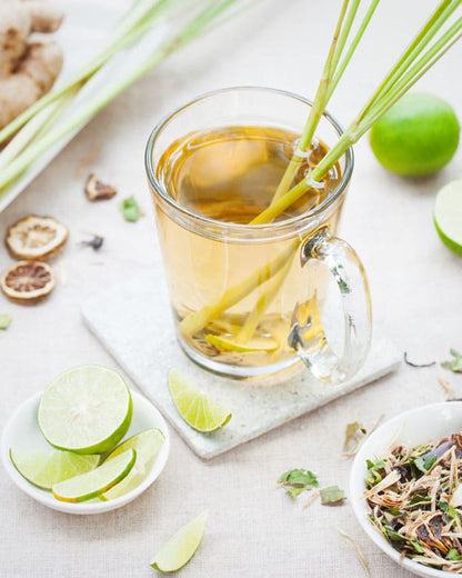 Fresh green tea lemongrass ingredients with limes, lemongrass stalks, and dried herbs
