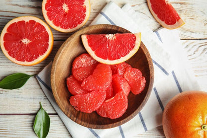 Fresh grapefruit slices in a wooden bowl, evoking citrus aroma oils for scent diffuser blends