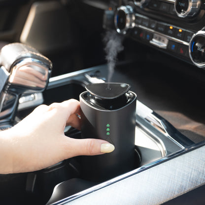 Portable scent diffuser emitting mist in a car cup holder, ideal for on-the-go aroma diffusion