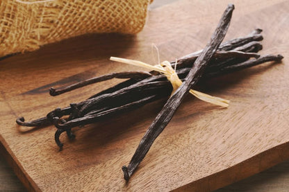 Fresh vanilla beans bundled on a wooden cutting board
