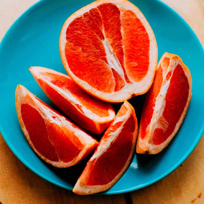 Sliced grapefruit segments on a teal plate showing deep red flesh