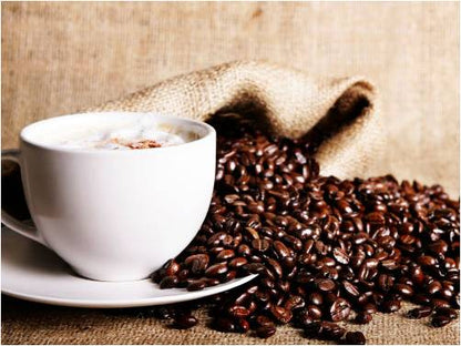 Steaming cappuccino cup surrounded by roasted coffee beans spilling from a burlap sack