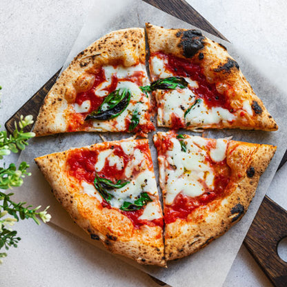 Neapolitan margherita pizza cut into four slices with mozzarella, tomato sauce, and fresh basil
