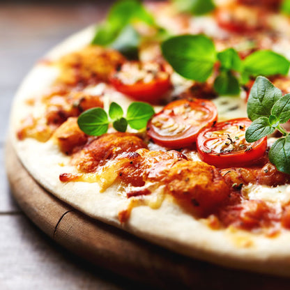 Close-up of a rustic pizza topped with cherry tomatoes, melted cheese, and fresh basil leaves