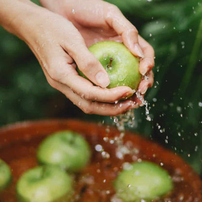 Hands washing fresh green apples in water, evoking clean, crisp scents used in aroma oils and scent diffusers