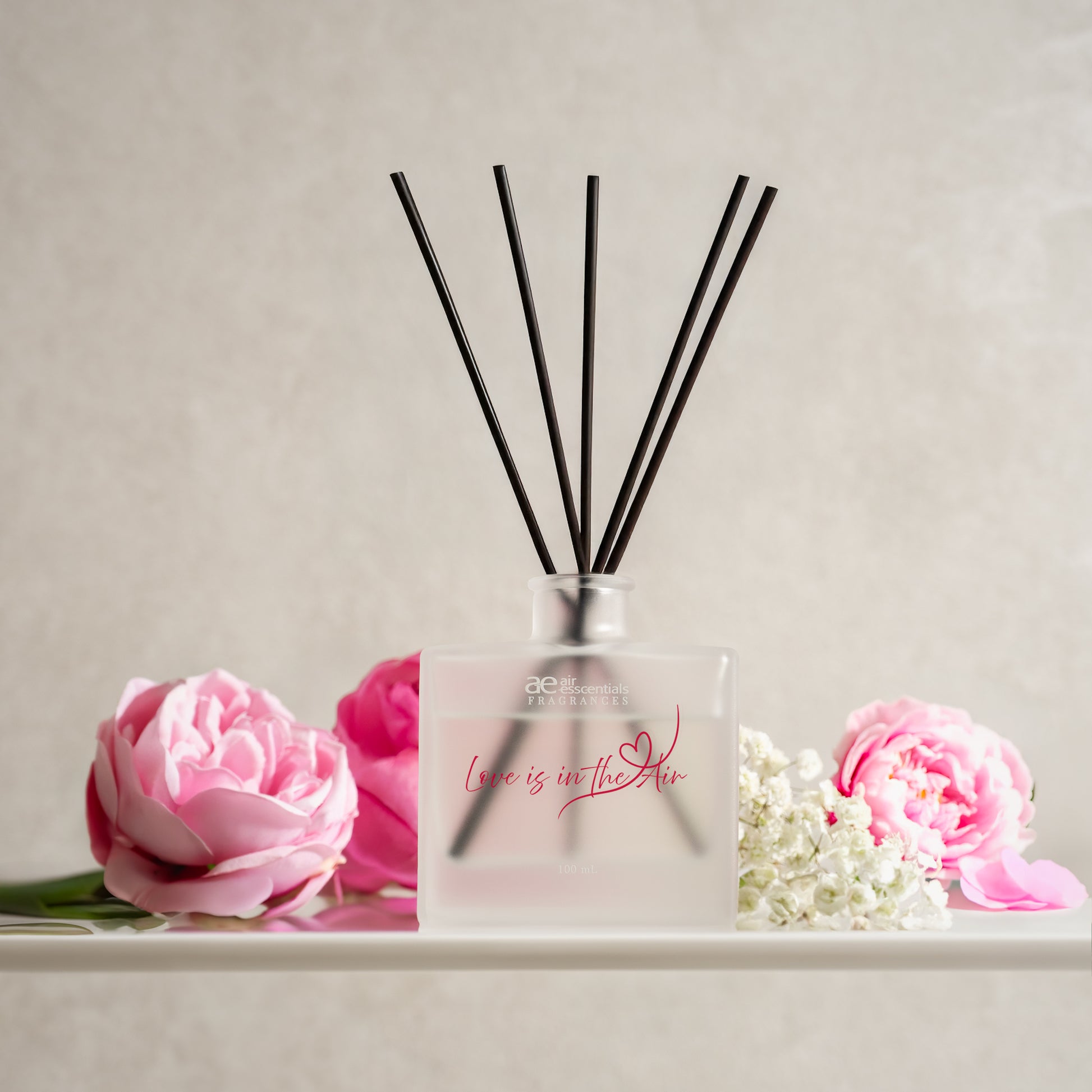 Diffuser with black sticks and pink flowers on a light background