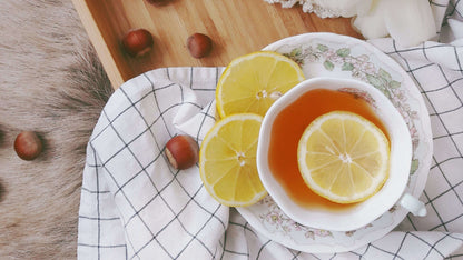Overhead view of lemon tea in a floral cup with hazelnuts, suggesting white tea scent diffuser inspiration