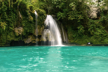 Tropical waterfall cascading into turquoise pool surrounded by lush green jungle foliage